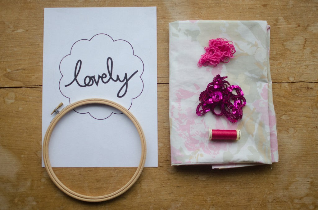 Flat lay of embroidery pattern and hoop with vintage fabric and pink embroidery thread