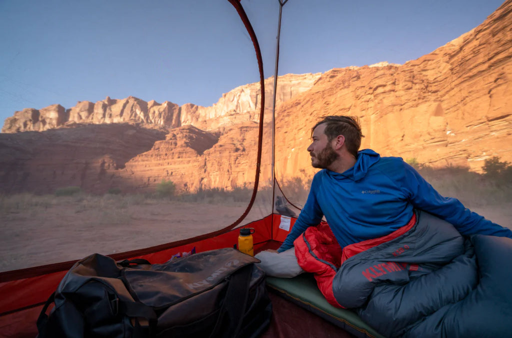 person laying in sleeping bag looking out of tent