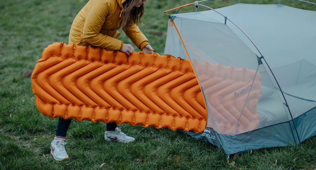 woman putting sleeping pad in tent