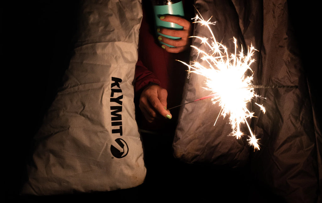 person wrapped in blanket with sparkler