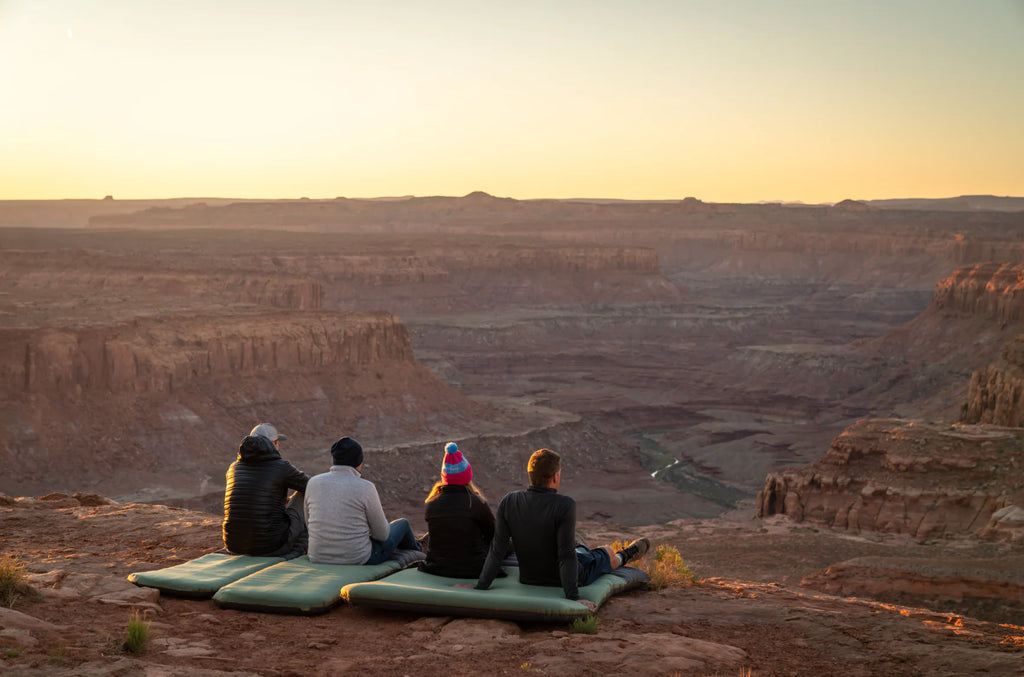 people sitting on sleeping pads looking at canyon view