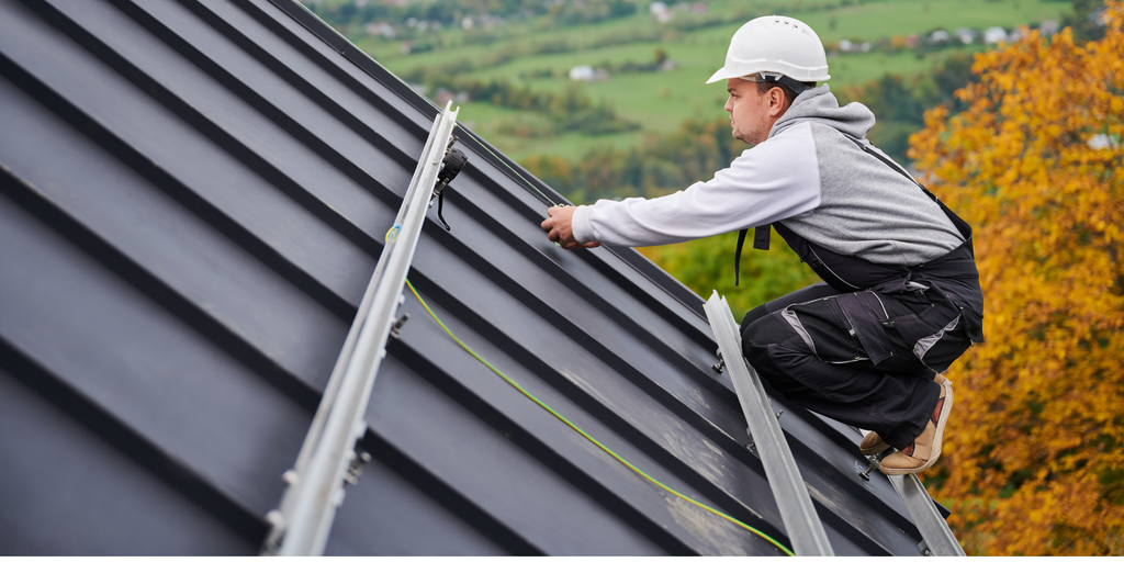 Ein Arbeiter montiert PV-Schienen auf dem Dach eines Kunden