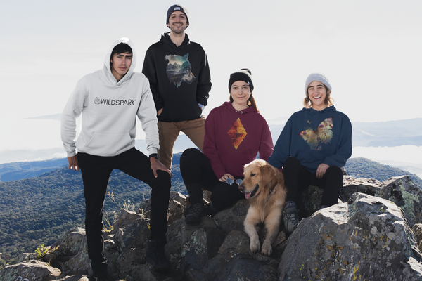 Ein Bild, das eine Gruppe von Freunden zeigt, die in Wildspark-Outdoor-Bekleidung auf einem Berggipfel stehen und die Aussicht genießen, um die Vorfreude auf ein Outdoor-Abenteuer zu vermitteln.