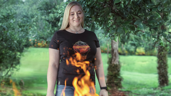 Maja stet vor dem Grill. Die Flammen lodern schön. Sie trägt ein Wildspark Organic Shirt für Damen aus Bio-Baumwolle mit dem Design Spark Sphere.