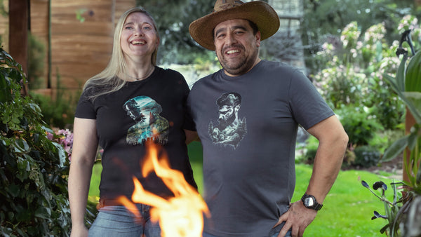 Maja und Hawk stehen im Garten vor einem Feuer. Beide tragen Organic Shirts von Wildspark aus der Nature's Realm Kollektion für Naturliebhaber.