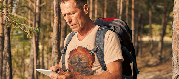 Ein Bild, das eine Person zeigt, die eine Landkarte studiert, während sie in der Wildnis steht, um die Bedeutung der Vorbereitung und Planung für ein Outdoor-Abenteuer zu betonen.