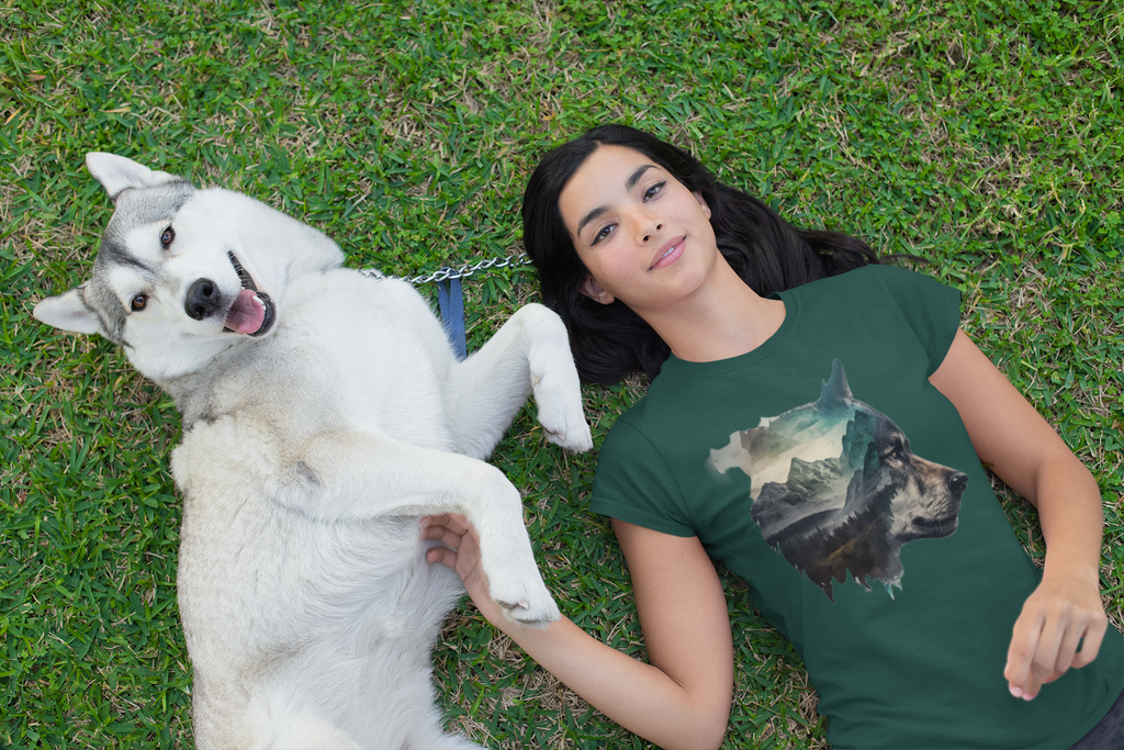 Eine junge Jägerin die mit einem Hund auf der Wiese liegt. Die Frau trägt das Mountain World Organic Shirt.