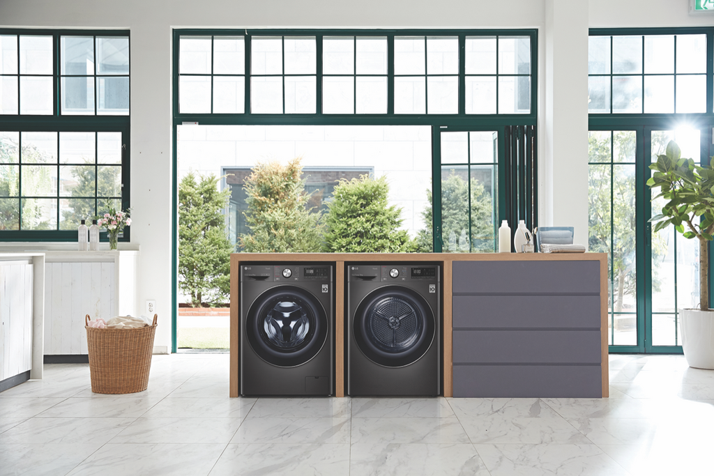 An LG front load washer and heat pump dryer in a dark stainless finish together in a modern laundry