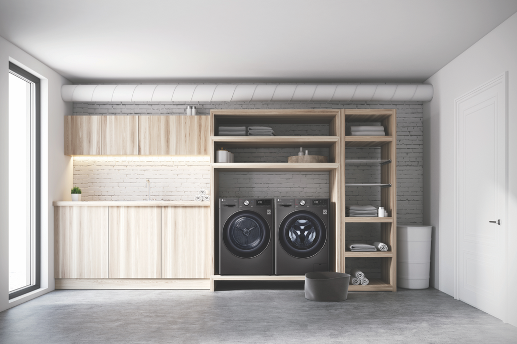 An LG front load washer and heat pump dryer in a dark stainless finish in a laundry with a white brick wall