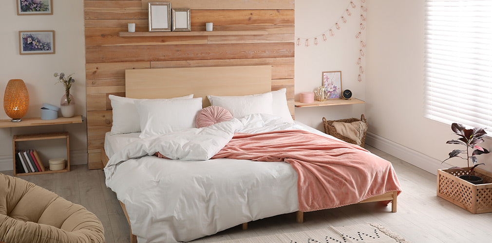 an image of a bed with a white blanket and pillow cases with a pink blanket thrown over one side