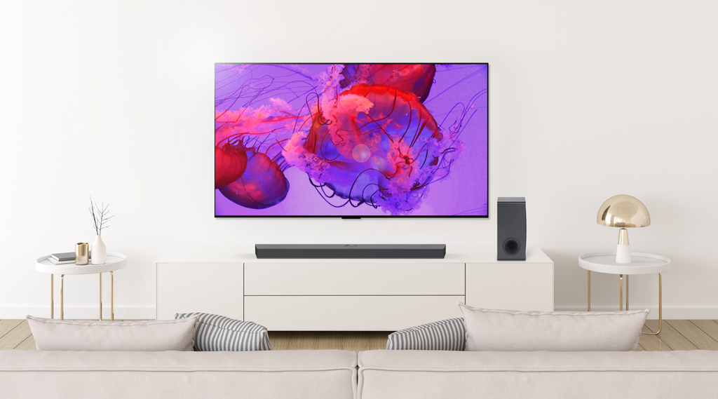 An LG OLED tv and matching soundbar on a light beige wall with a pink and purple image on the screen