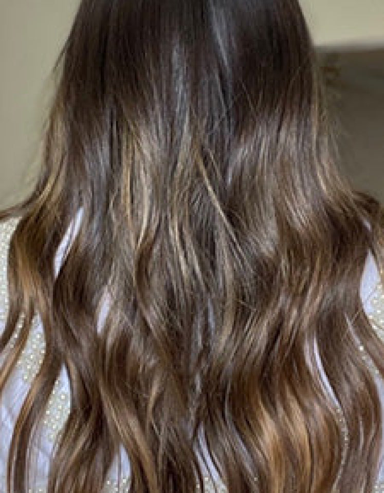 Long wavy brown hair with highlights.