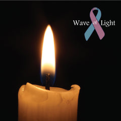 one burning candle with a wave of light pink and blue ribbon