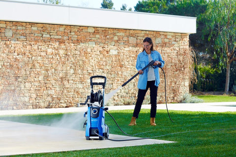 woman cleaning a patio with a blue pressure washer