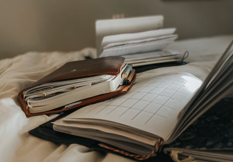 An open planner and closed cover on a bed