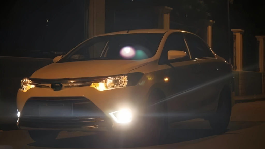 Toyota sedan with bright LED fog lights glowing in nighttime setting.