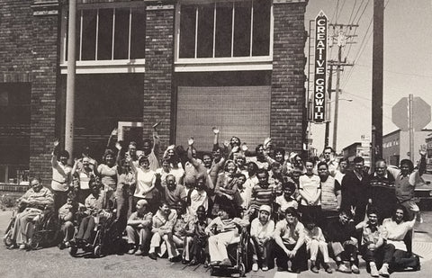 A black and white historical photo of a large group posing outside ofCreative Growth Center