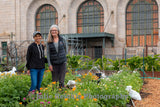 Two women posing in a garden in front of an ornate building