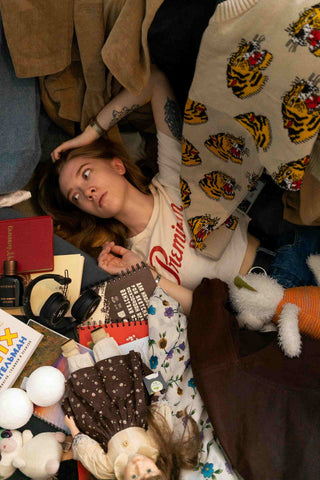 girl lying on messy floor surrounded by tons of things