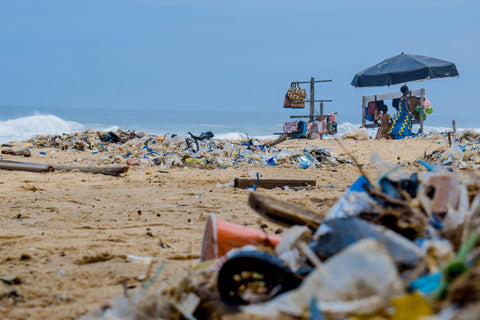 sandy beach coveredin piles of liter and garbage washed up from the ocean and left by consumers