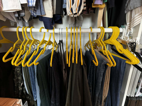 yellow (re)x hangers holding pants on a bottom closet shelf