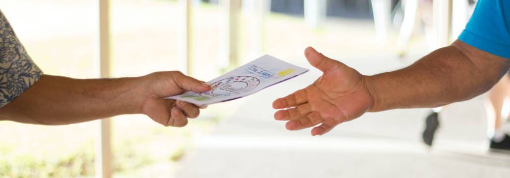 A hand holding out a Christian gospel tract.