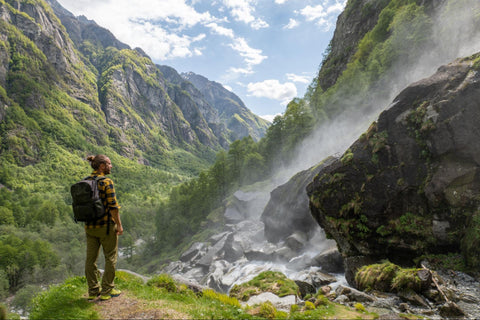 Un randonneur regardant gracieusement une cascade et un magnifique canyon