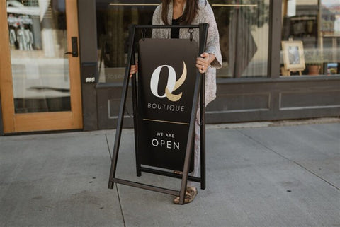 Shop owner setting out a black metal sidewalk sign