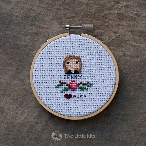 A small cross-stitched "head shot" of a woman with a floral decoration underneath.