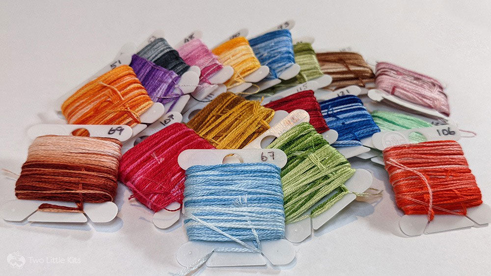 Lots of DMC variation flosses stacked neatly in a floss container