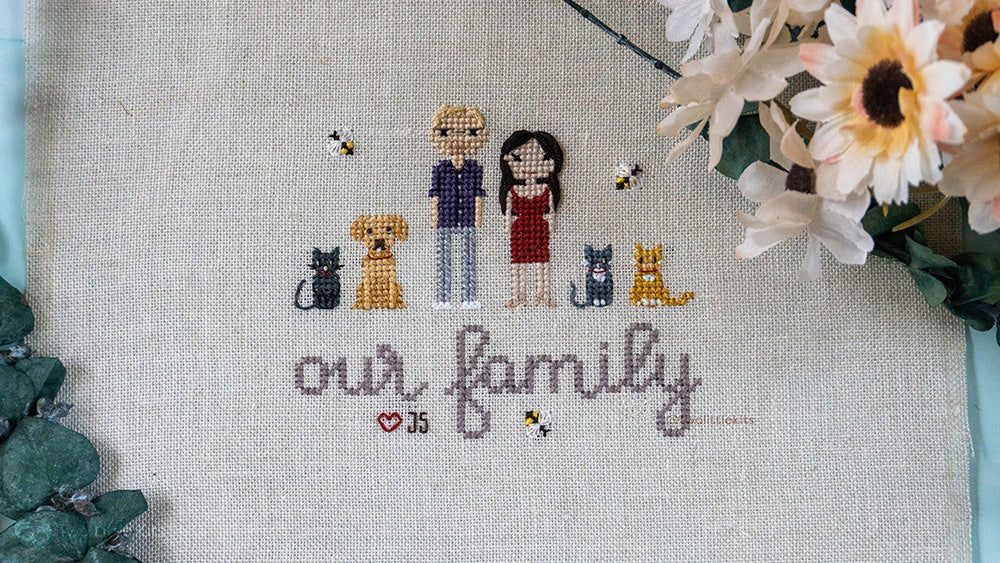A stitch peple piece with two people, three cats and one dog. There is a large "Our Family" underneath them all and decorated with three tiny little bees.
