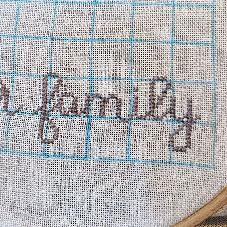 Early stitching WIP of the rush order. You can see the 10x10 grid drawn on in blue and the word "family" cross-stitched.