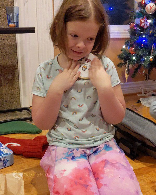 A photo of a little girl on Christmas morning, hugging a cross-stitch