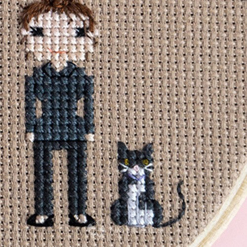 A stitched woman and cat on brown fabric.