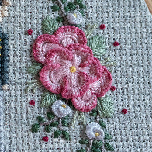 Photo of hand embroidered florals. There are a lot of different stitches being used for this section and the piece is very intricate.