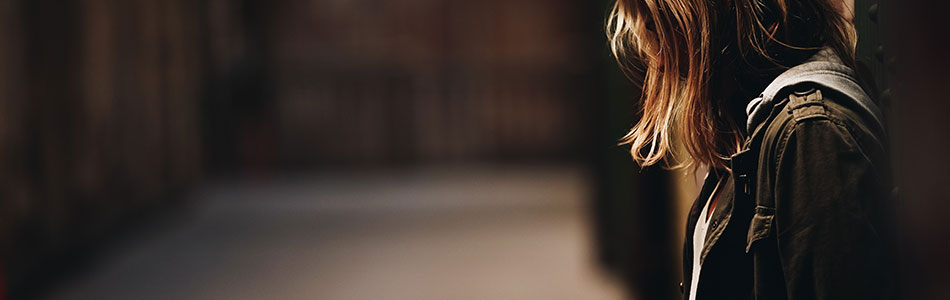 A stock photo of a woman, alone in a dark alley