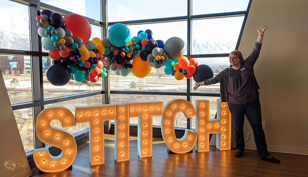 Kate beside a bit blocky "STITCH" word with balloon decoration