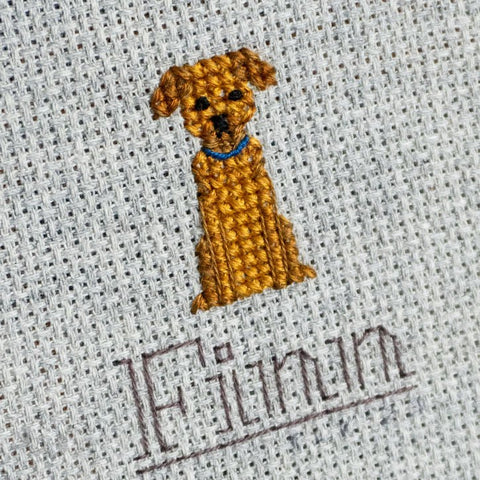 A close-up of a cross-stitched dog in an embroidery hoop