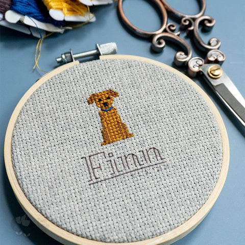 A close-up of a cross-stitched dog in an embroidery hoop