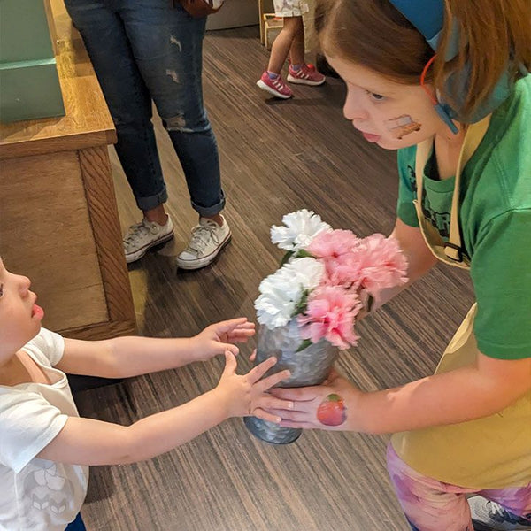 A little toddler handing flowers to Charlie at a kids museum