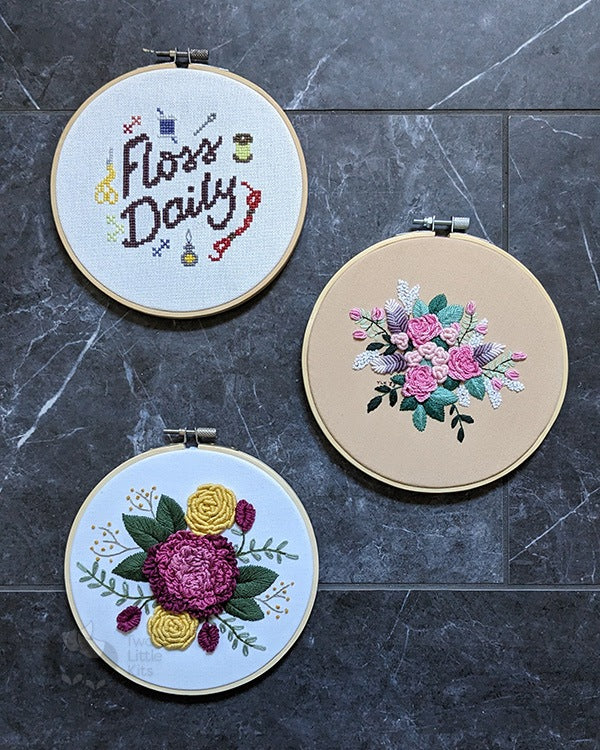 Three completed pieces of work; one cross-stitch and two hand embroideries.