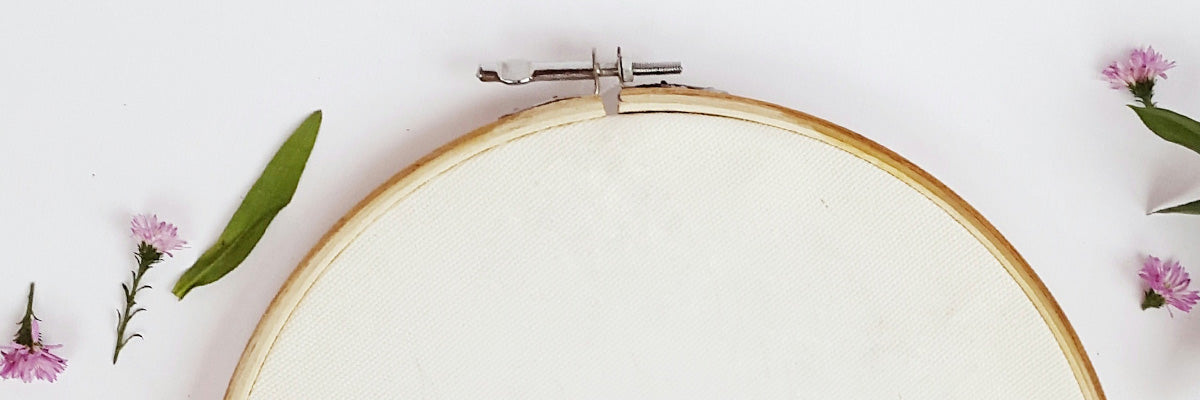 A cropped photo of a blank embroidery hoop with small flora bits and pieces around it