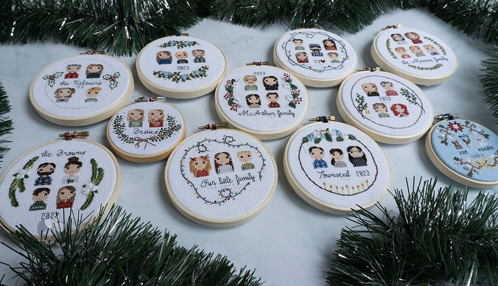 11 completed cross-stitch holiday ornaments laid out flat together.