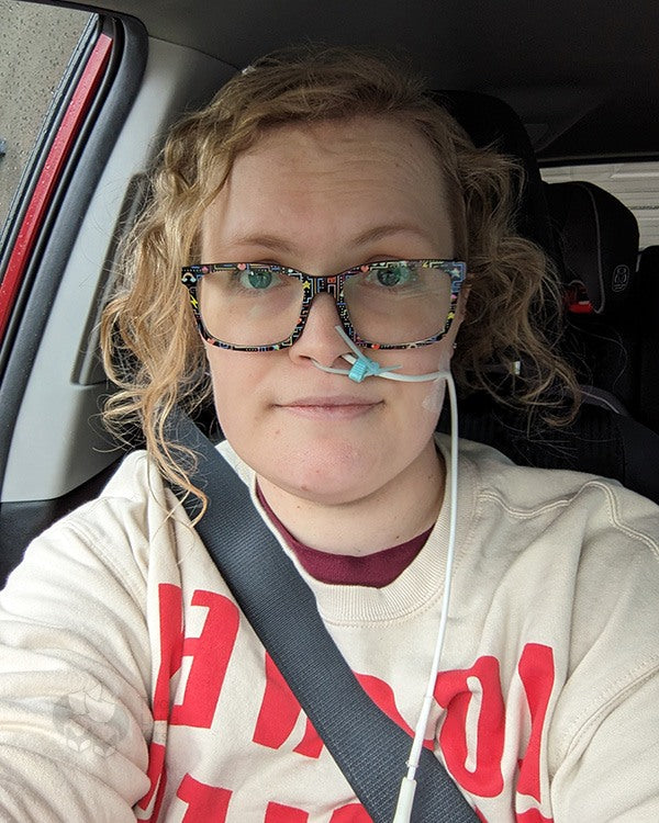 Kate sitting in her car with a feeding tube coming out of her nose.