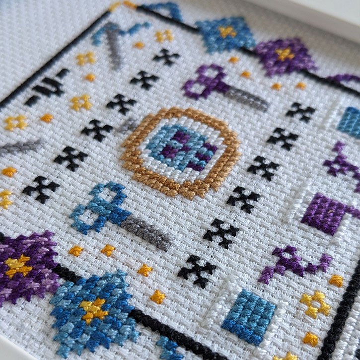 A close-up of "The Stitcher" cross-stitch piece