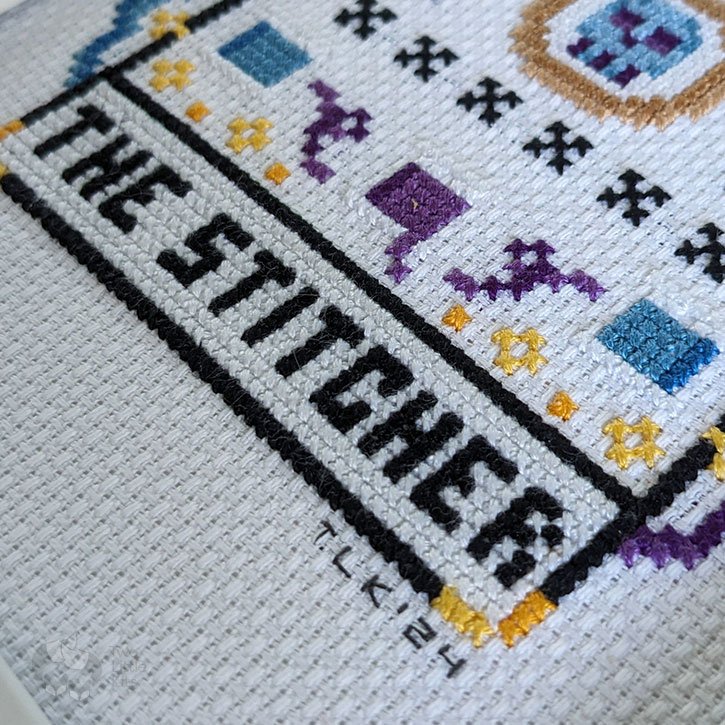 A close-up of "The Stitcher" cross-stitch piece