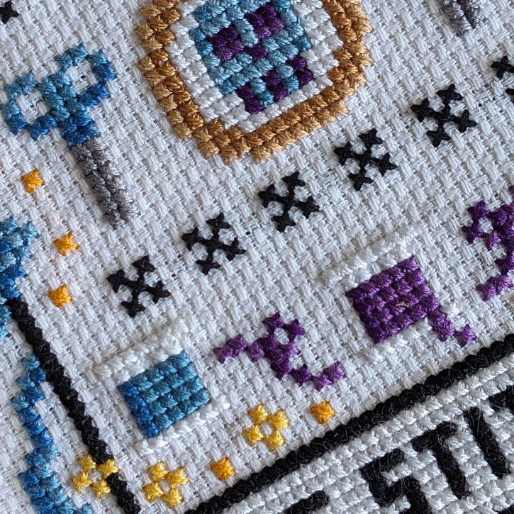 A close-up of "The Stitcher" cross-stitch piece