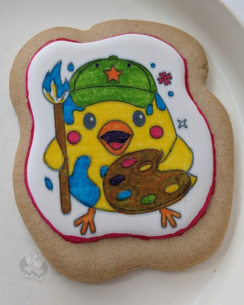 A coloured-in cookie where the image is a baby chick making a mess of painting.