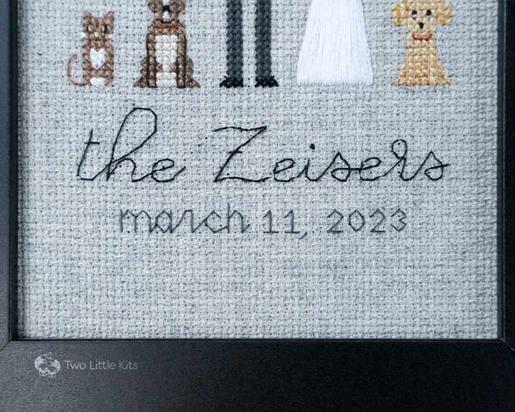 A cross-stitch piece depicting backstitching words that read "the Zeisers. March 11 2023". The photo is up-close to the piece itself.