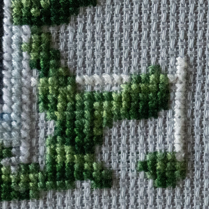 A close-up photo of the details of a cross-stitched house piece